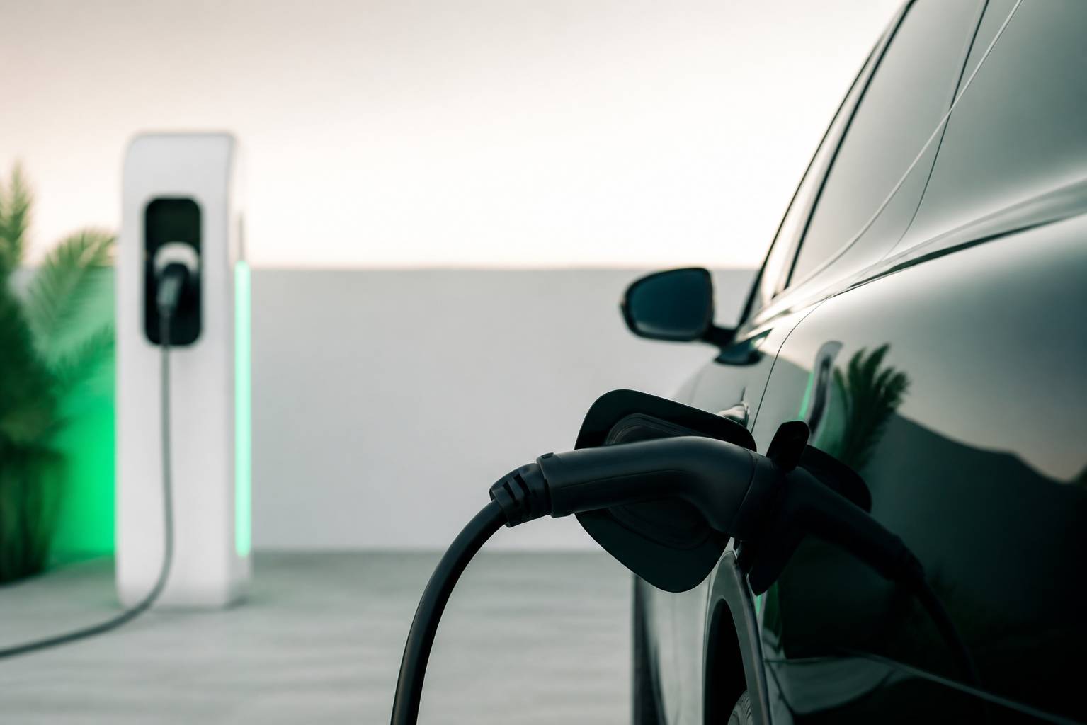 Câble de recharge branché sur une voiture électrique, borne en arrière-plan