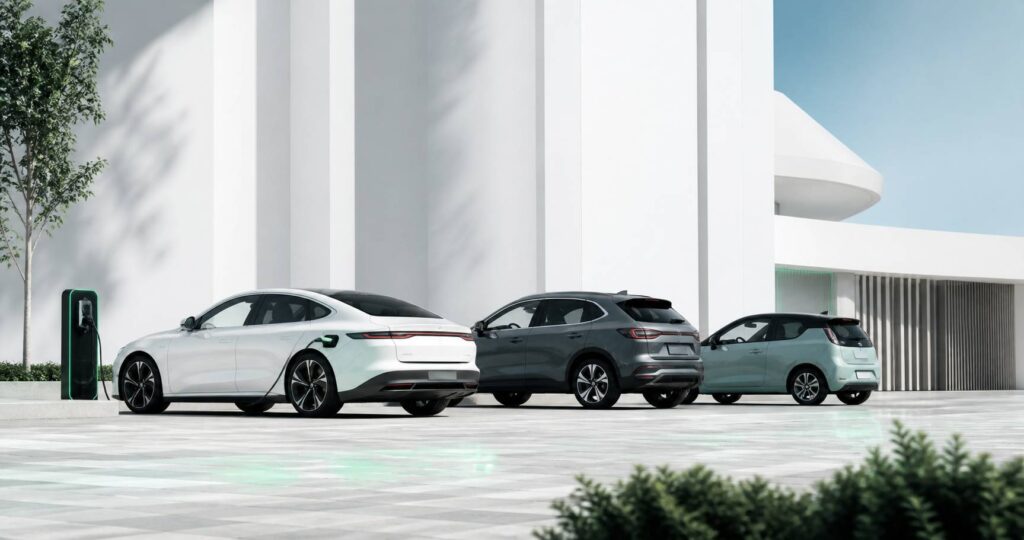 Trois voitures modernes dont une électrique branchée à une borne